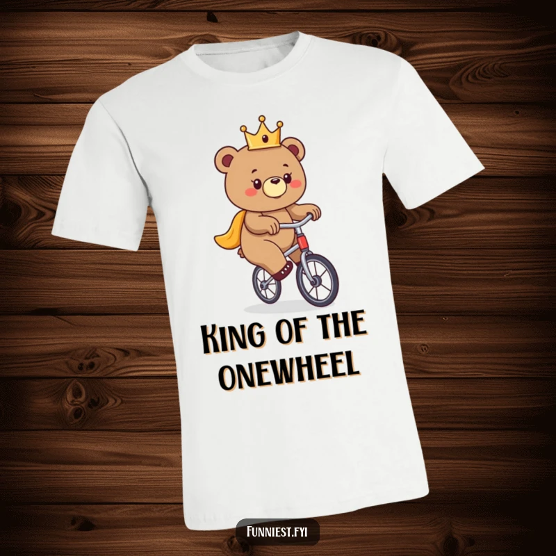 Funny bear t-shirt, a bear donned in a tiny crown struggles comically to ride a unicycle.
